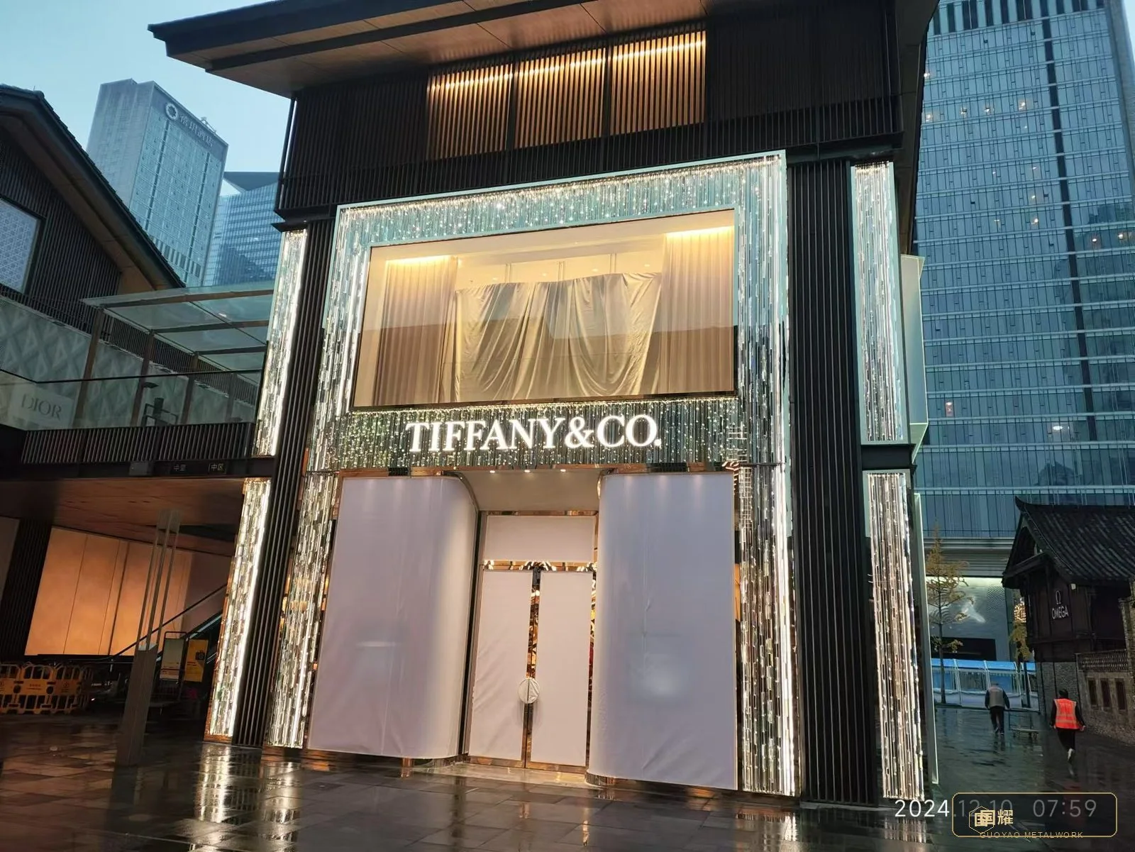 Luxury jewellery boutique facade with backlit brushed metal panels at night