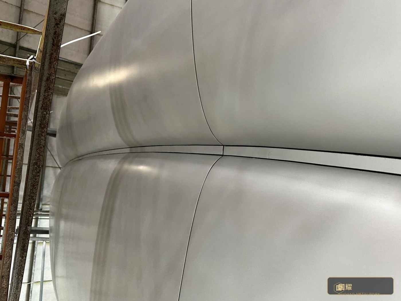 Tight seam between curved metal-clad columns in a luxury residential lobby