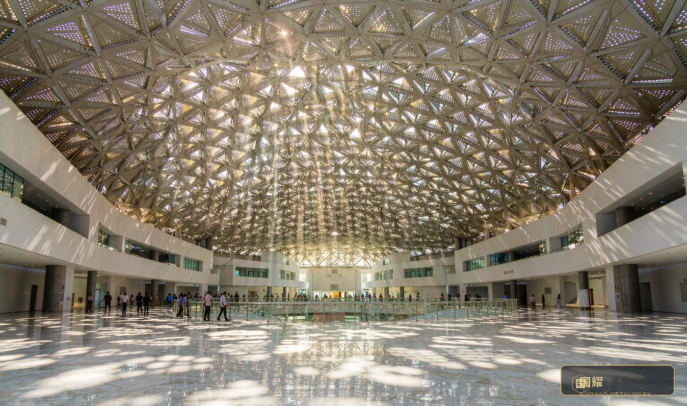Museum atrium under a perforated steel and aluminium dome casting a rain of light