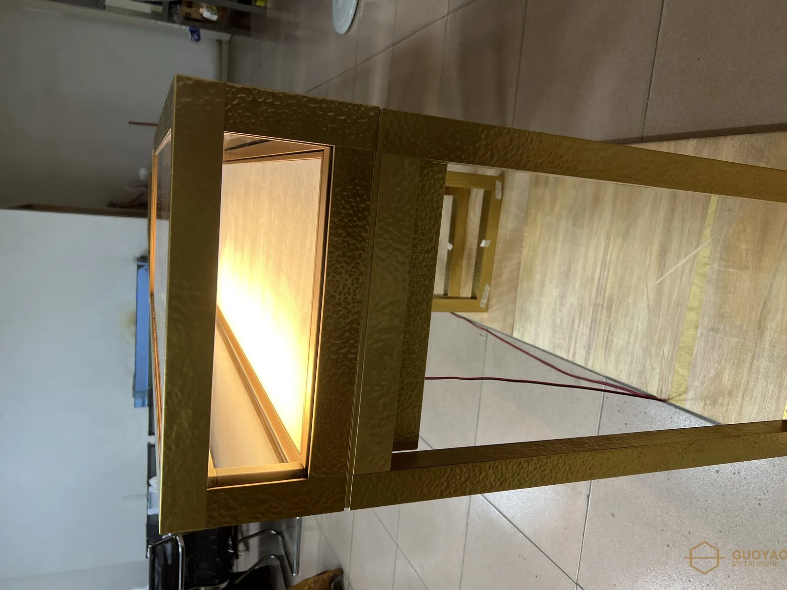 Backlit hammered brass display vitrine glowing evenly in a hotel lobby