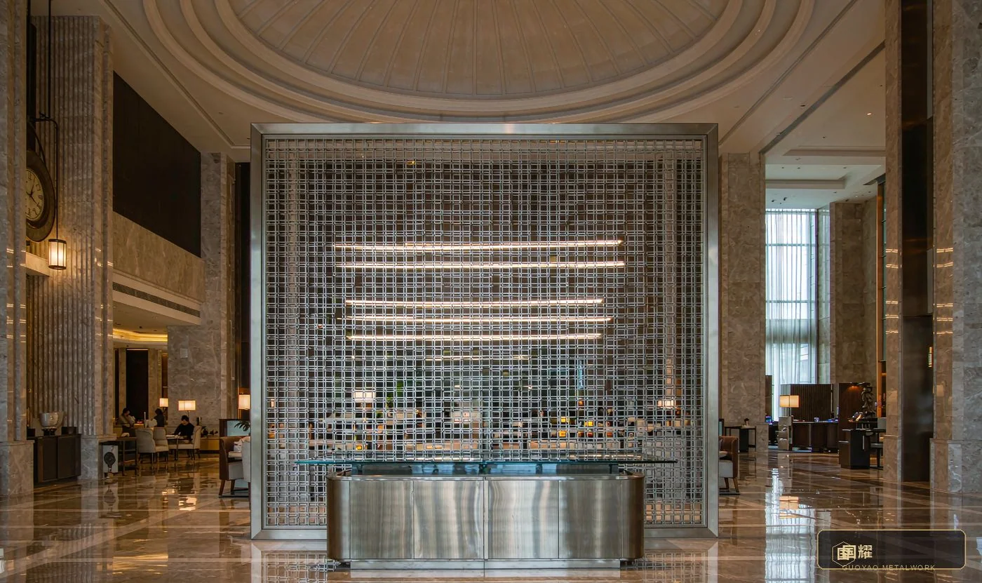 Hotel lobby in the field: etched-texture metal screen and brushed reception counter with concealed lighting